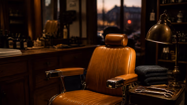 Intérieur chaud de barbier, fauteuil cuir et lumière basse, sans visages identifiables.